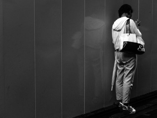 工事中の壁の前でスマホを弄る女性の後ろ姿