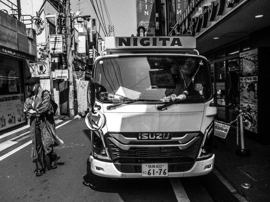 停車中の作業車、その横を通り過ぎる若い女性