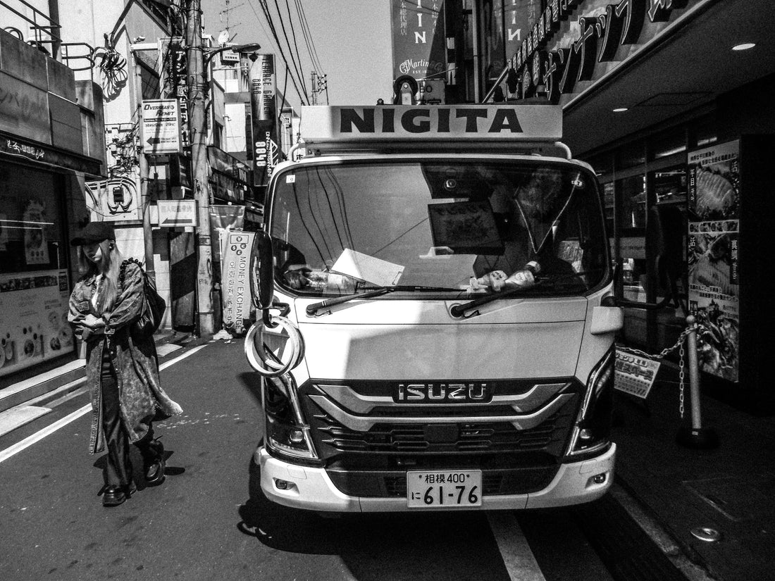 停車中の作業車、その横を通り過ぎる若い女性